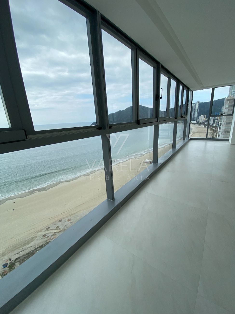 Varanda envidraçada de apartamento em Balneário Camboriú com vista frontal para a praia